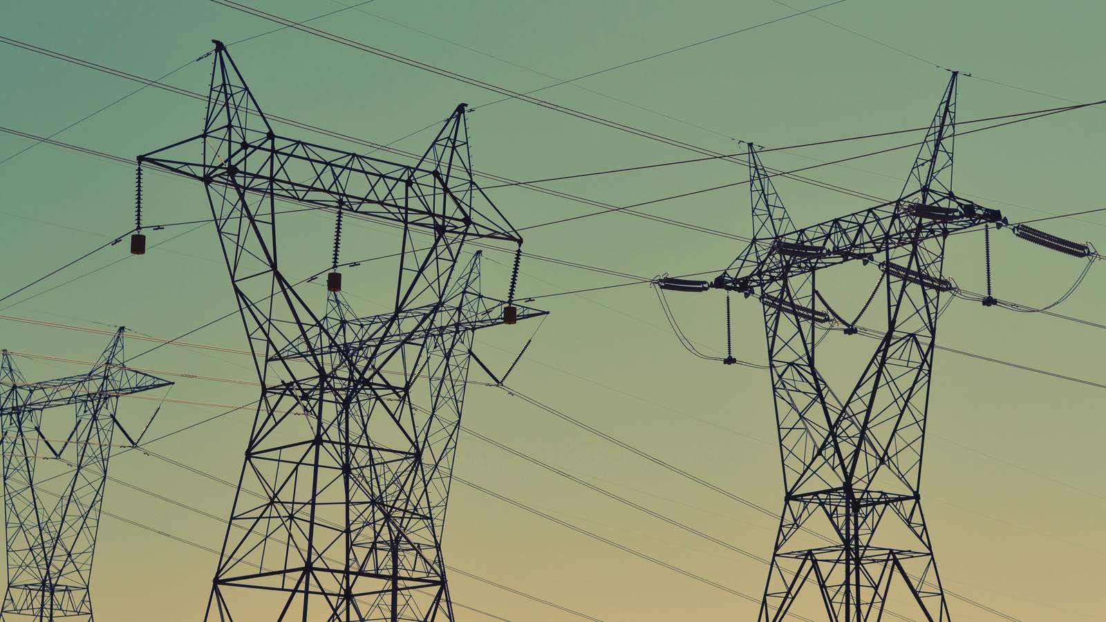 Pylônes électriques et lignes à haute tension, sous un ciel vert